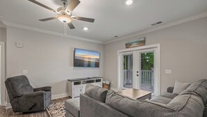 A living room with a gray sofa, a gray armchair, a white entertainment unit, and a ceiling fan. - Brand NEW Calabash Condo (Calabash)