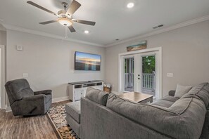 A living room with a gray sofa, a gray armchair, a white entertainment unit, and a ceiling fan. - Brand NEW Calabash Condo (Calabash)