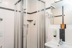 A modern bathroom with a glass-enclosed shower, a white sink, and a mirror above it.