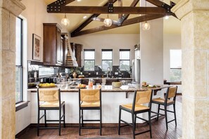 A kitchen with a central island, bar stools, and a stone column.