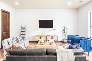 A modern living room with a sofa, coffee table, and a flat-screen TV mounted on the wall.