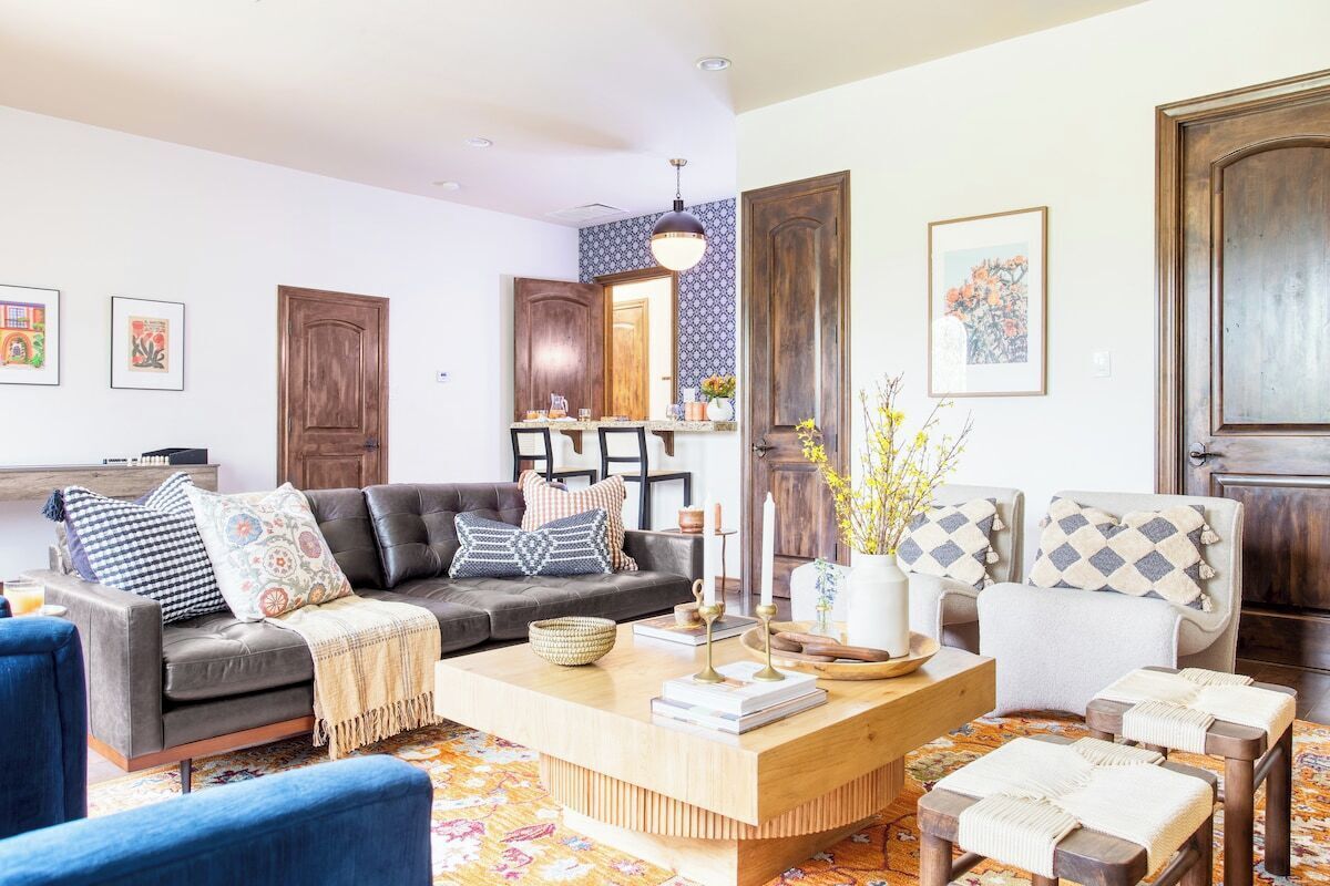Een woonkamer met een bank, fauteuils, een salontafel en een kamerkleed met een patroon.