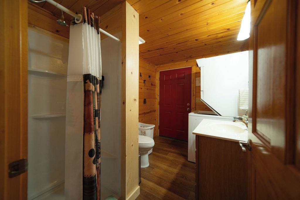 A wooden interior with a shower, toilet, and sink.