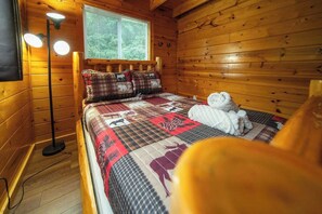 Una camera da letto in una casetta di legno, con un letto, una finestra e una lampada da terra.