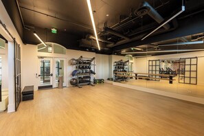 Une salle de sport spacieuse dotée d’un plancher en bois, d’équipements d’exercice et d’un mur recouvert de miroirs.