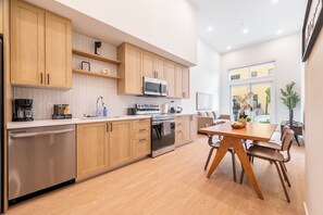 Een moderne keuken met houten kastjes, een RVS vaatwasser, een inbouwoven en een koffiebar.