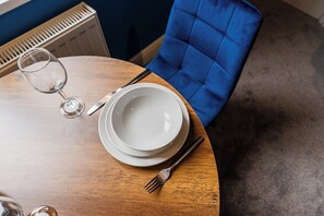 A round wooden table with a white plate, a fork, and a glass of water. - Cozy Blue Ember Stay | Work friendly 4BR+Sleeps 7 (Redcar and Cleveland)