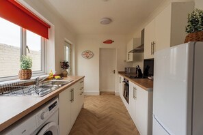 A compact kitchen with a washing machine, a microwave, and a refrigerator. - Cozy Blue Ember Stay | Work friendly 4BR+Sleeps 7 (Redcar and Cleveland)