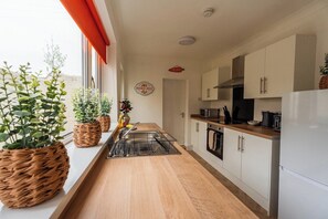 A modern kitchen with white cabinets, a stainless steel sink, and a built-in oven. - Cozy Blue Ember Stay | Work friendly 4BR+Sleeps 7 (Redcar and Cleveland)