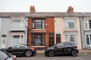 A row of terraced houses with a black car parked in front. - The Alfred Suite | Redcar (Redcar and Cleveland)