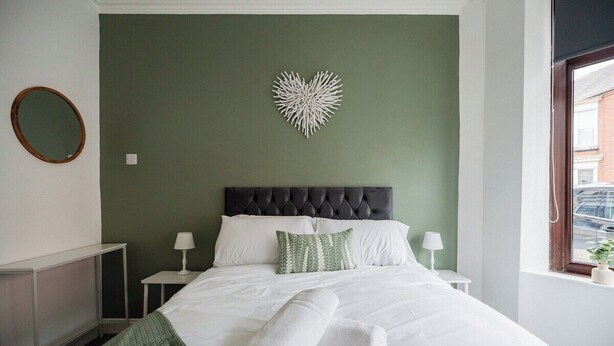 A hotel room with a bed, two bedside tables, a mirror, and a decorative wall piece. - The Alfred Suite | Redcar (Redcar and Cleveland)