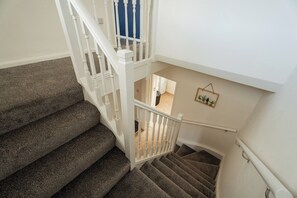 A staircase with carpeted steps and white balusters. - 3BR Barnaby House | Contractor Friendly | Sleeps 5 (Redcar and Cleveland)