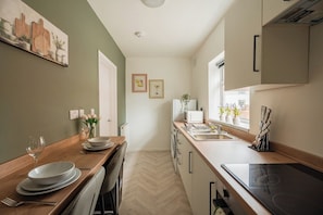 A narrow kitchen with a wooden countertop, a built-in oven, and a window with potted plants. - Stunning Laburnum House | 4BR | Parking | Sleeps 7 (Redcar and Cleveland)