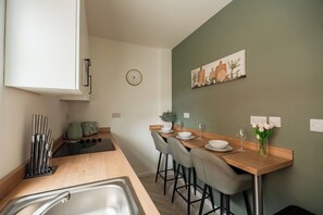 A modern kitchen with a wooden countertop, stainless steel sink, and bar stools. - Stunning Laburnum House | 4BR | Parking | Sleeps 7 (Redcar and Cleveland)