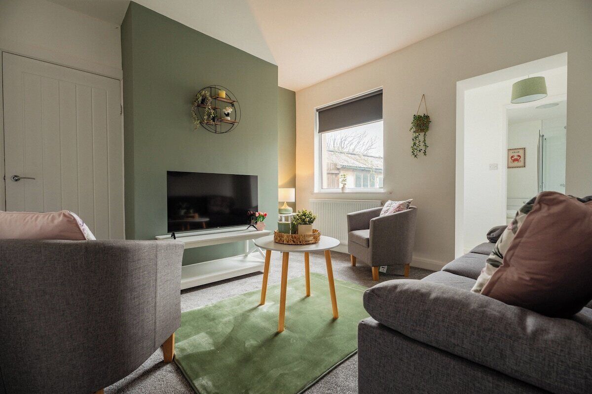 A living room with a television, a sofa, a small table, and a window with a view.