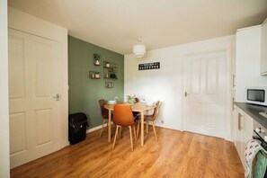 A compact kitchen with a dining table, chairs, and a microwave. - 3BR Einstein House in Hardwick | Work Friendly (Stockton-on-Tees)