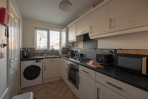 Een kleine keuken met een wasmachine, oven en een magnetron.