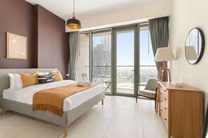 A modern hotel room with a large bed, a desk, a chair, and a balcony with a city view. - Silkhaus City View 3BR Nearby Canal in Al Wasl (Dubai)