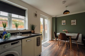 A kitchen with a dishwasher, a sink, and a window with a view of a garden. - Spacious 3BR in Babbage Gardens | Sleeps 5+Wifi (Stockton-on-Tees)