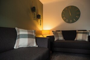 Ein Wohnzimmer mit zwei Sofas, einer Wanduhr und einer Lampe.