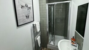 A bathroom with a glass-enclosed shower, a white sink, and a framed picture on the wall. - 6 Bed Contractor Acom in Hartlepool (Hartlepool)