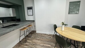 A modern kitchen with a granite countertop, bar stools, a dining table with chairs, and a framed sign on the wall. - 6 Bed Contractor Acom in Hartlepool (Hartlepool)