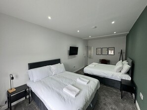 Ein Hotelzimmer mit zwei Betten, einem Fernseher, einem Schreibtisch und einem Stuhl.