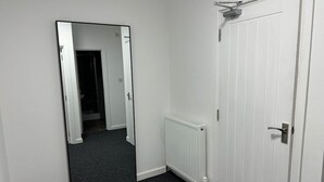 A hallway with a white door, a radiator, and a mirror reflecting a bathroom. - 6 Bed Contractor Acom in Hartlepool (Hartlepool)