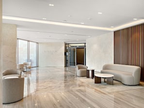 Eine moderne Lobby mit Fischgrätparkett, Sitzbereichen und einer Wand mit dem Schriftzug "CANAL FRONT RESIDENCES CF9A".