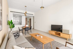 Ein modernes Wohnzimmer mit einer Couch, einem Couchtisch, einem Fernseher und einem Essbereich mit Stühlen und einem Tisch.