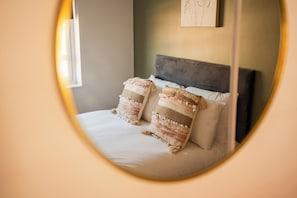 A bed with two pillows and a headboard in a room with a window and a wall-mounted artwork. - 3BR Norton Nook | Sleeps 5 | Work Friendly + WiFi (Stockton-on-Tees)