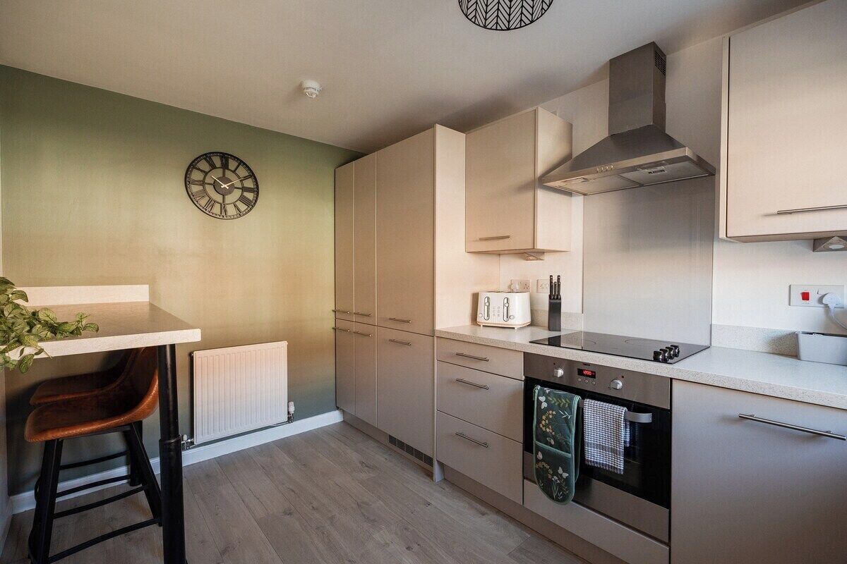 A modern kitchen with a built-in oven, a toaster, and a clock on the wall.