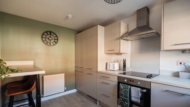 Una cocina moderna con horno empotrado, tostadora y un reloj en la pared.