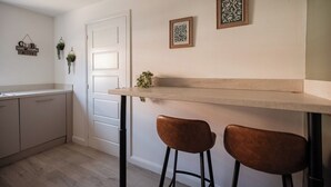 Una cocina con una puerta blanca, dos taburetes y plantas colgantes en la pared.