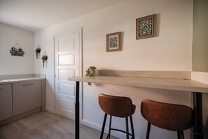 A kitchen with a white door, two stools, and wall-mounted greenery. - The Norton Nook | Horizon Stays (Stockton-on-Tees)