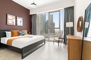 Ein modernes Hotelzimmer mit einem großen Bett, einem Schreibtisch, einem Sessel und Blick auf die Stadtlandschaft.