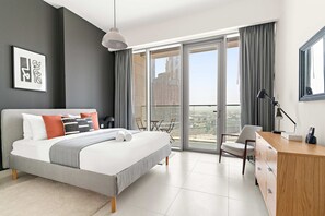 Ein modernes Hotelzimmer mit einem großen Bett, einem Schreibtisch und einem Balkon mit Blick auf die Stadt.