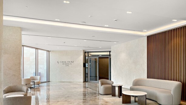A modern lobby with a herringbone floor, seating areas, and a wall with the text "CANAL FRONT RESIDENCES CF9A". - Silkhaus Luxe 3BR Apartment by the Canal (Dubai)