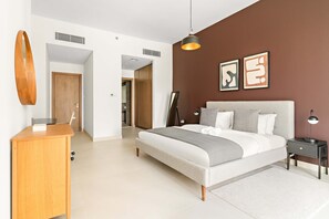 Ein modernes Schlafzimmer mit einem Bett, Nachttischen, einem Schreibtisch und Kunstwerken an der Wand.