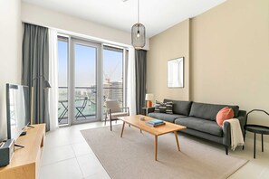 Ein modernes Wohnzimmer mit einer Couch, einem Couchtisch, einem Fernseher und Blick auf eine Baustelle durch große Fenster.