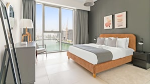 A modern hotel room with a large bed, a desk, and a view of a cityscape. - Silkhaus Contemporary 2BR Canal View Stay (Dubai)