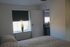 A bedroom with a bed, a window with a plant, a radiator, and a door leading to a bathroom. - Welcoming 4BR Thornaby Home | Pool Table+Sleeps 8 (Thornaby)