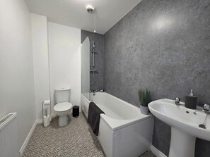 Een badkamer met een toilet, een bad en een wastafel.