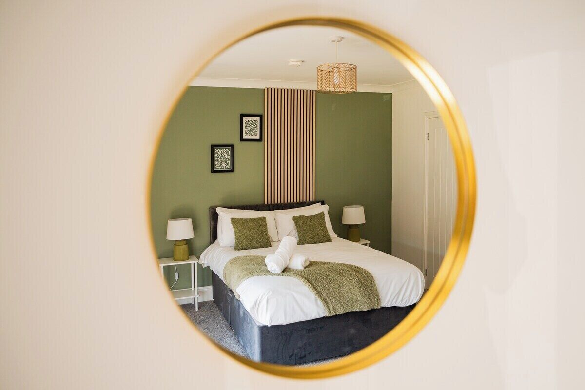 A bedroom with a bed, two bedside tables, a lamp, and a mirror.