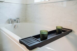 Eine Badewanne mit einem schwarzen Tablett, auf dem zwei Kerzen stehen.