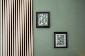 Eine Wand mit zwei gerahmten Pflanzenbildern und einer vertikalen Holzhakendesign.
