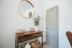 A wooden console table with a mirror, a vase with green foliage, and a bowl. - Stylish 3BR Bungalow with Garden | Sleeps 6 (Redcar and Cleveland)