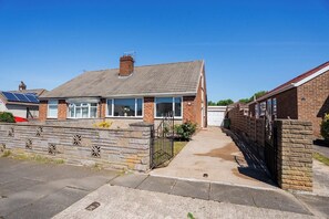 A residential property with a brick facade, a tiled roof, and a gated entrance. - Stylish 3BR Bungalow with Garden | Sleeps 6 (Redcar and Cleveland)
