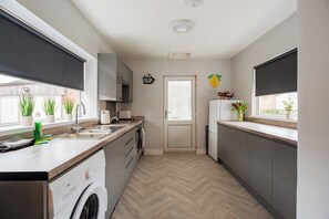 Eine kompakte Küche mit Waschmaschine, Spüle und einem Fenster mit Blick.