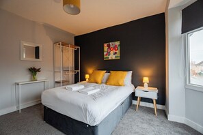 A modern hotel room with a large bed, bedside tables, a window, and a shower area. - 4BR Humber House for 7|Contractor Stay|Thornaby (Thornaby)